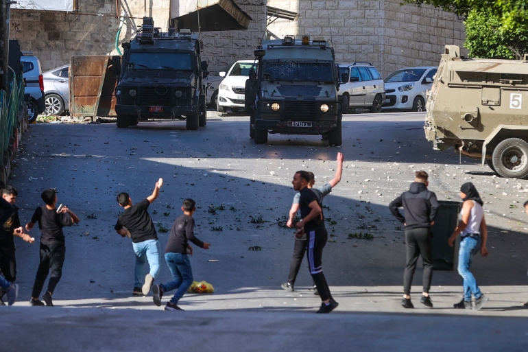 Palestinians throw stones at Israeli forces as they clash during an Israeli army raid in the occupied West Bank city of Nablus on May 4, 2023. - Israeli troops killed three people in a raid on the West Bank city of Nablus on May 4, the Palestinian health ministry said. (Photo by Zain Jaafar / AFP)