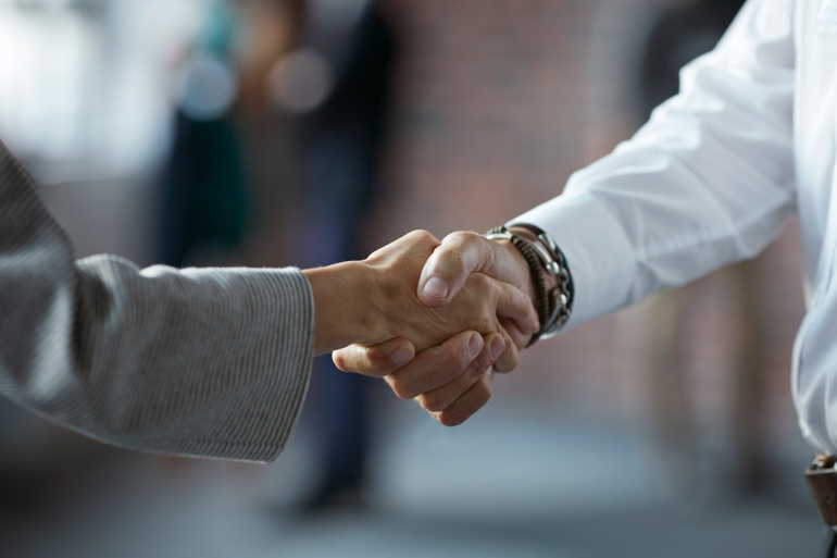 Close-up of businessman & businesswoman making handshake at convention