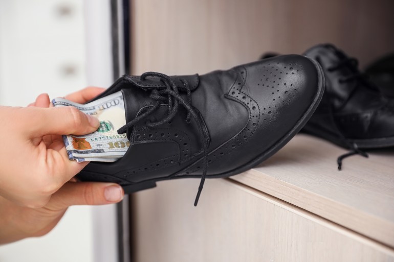 Woman hiding money in shoe indoors, closeup. Financial savings