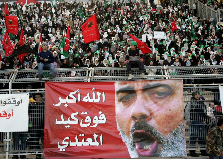 People protest against Israeli air strikes on the Gaza Strip, in front of a banner with a picture of Senior Hamas leader Ismail Haniyeh, at Amman stadium January 2, 2009. The banner reads "Gods will is greater than the enemy's folly".