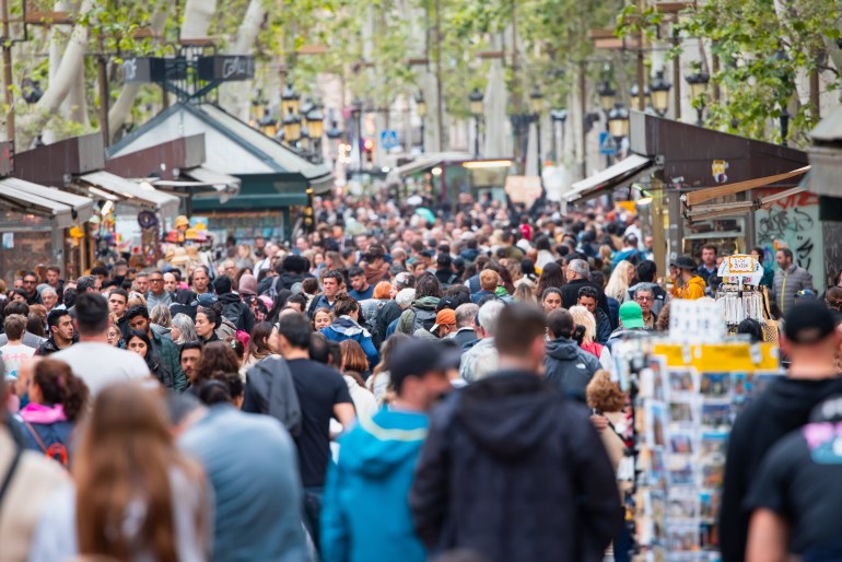 Barcelona, Spain - April 27 2024: Crowds of tourists walking on La Rambla street in Barcelona, Spain