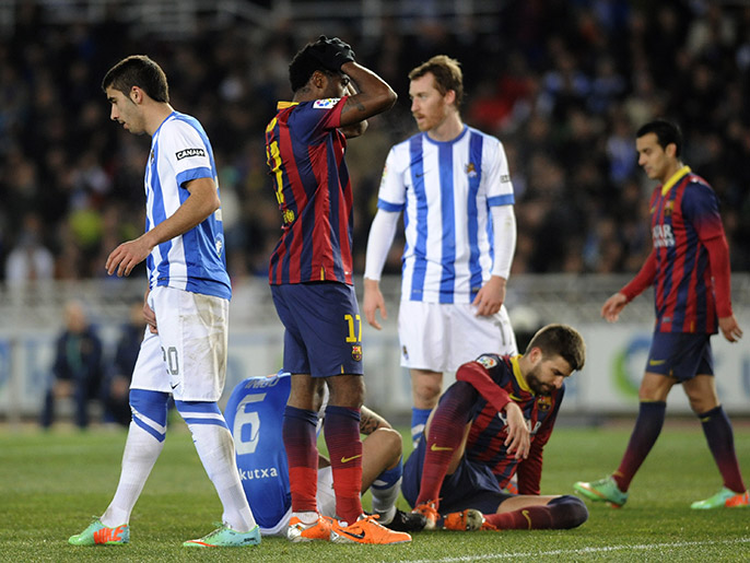 Barcelona's Cameroonian midfielder Alexandre Song (2L) stands as defender Gerard Pique (Down) sits on the field during the Spanish league football match Real Sociedad vs FC Barcelona at the Anoeta stadium in San Sebastian on February 22, 2014. AFP PHOTO / ANDER GILLENEA