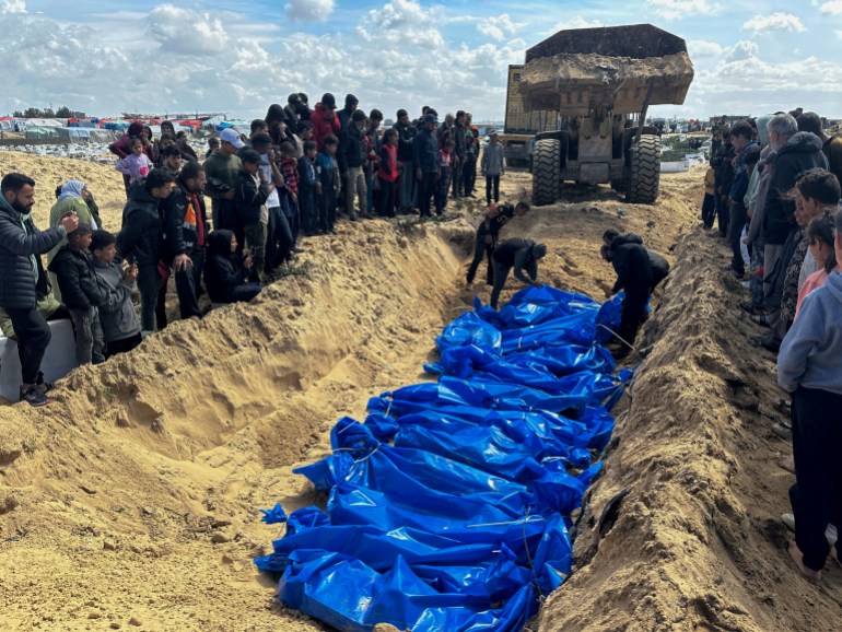 People bury the bodies of Palestinians killed in Israeli strikes and fire, after their bodies were released by Israel, amid the ongoing conflict between Israel and the Palestinian Islamist group Hamas, at a mass grave in Rafah, in the southern Gaza Strip, March 7, 2024. REUTERS/Mohammed Salem