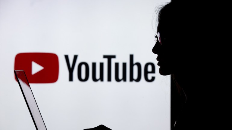 Digital Applications- - ANKARA, TURKEY - JULY 18 : A silhouette of a woman with a laptop is seen in front of the logo of Youtube application in Ankara, Turkey on July 18, 2018.