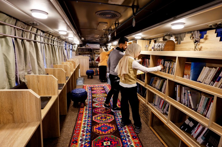 People browse books in a new solar-powered, environmentally friendly mobile library, the first of its kind in the city since its liberation in Mosul, Iraq, November 15, 2024. REUTERS/Khalid Al-Mousily