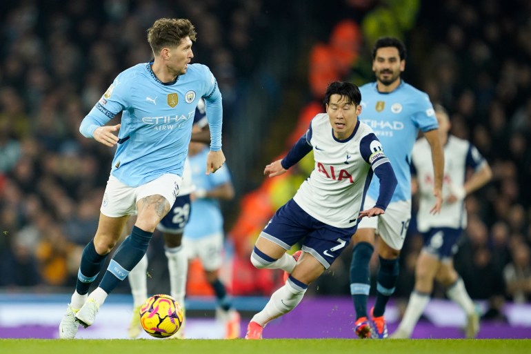 Manchester City's John Stones, left, is chased by Tottenham's Son Heung-min during the English Premier League soccer match between Manchester City and Tottenham at the Etihad Stadium in Manchester, England, Sunday, Nov. 24, 2024. (AP Photo/Dave Thompson)