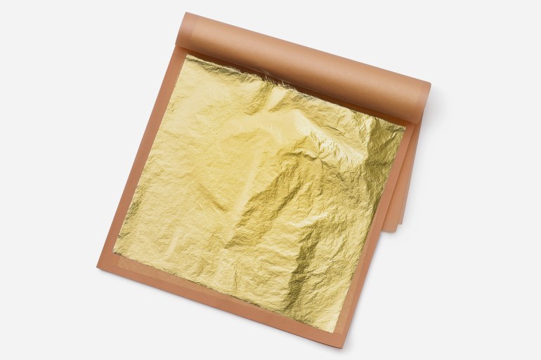 Top view of 24K natural edible gold leave sheets isolated on white