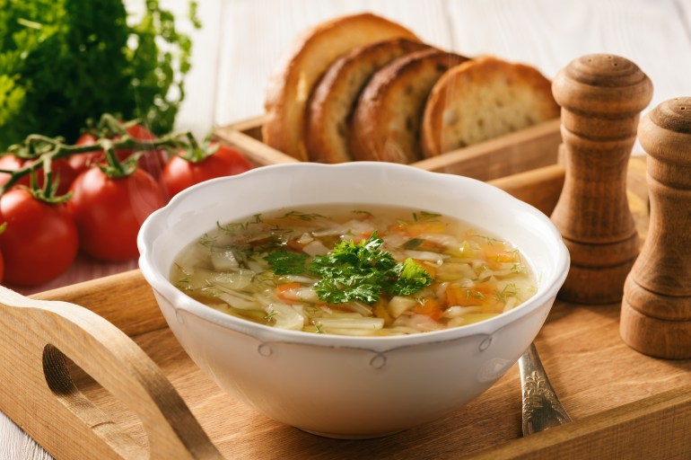 Vegetable soup with bread on wooden tray.