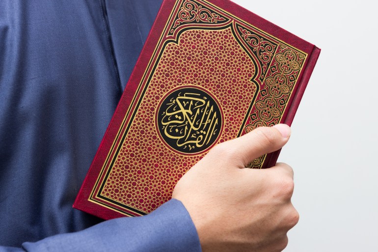 Koran in hand. Arabic word translation : The Holy Al Quran (holy book of Muslims) - public item of all muslims