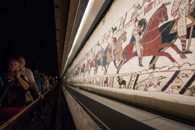 People look at the "Bayeux tapestry" or "Queen Mathilde tapestry" which relates Britain's conquest by William the Conqueror (Guillaume le Conquerant) in 1066, in Bayeux, western France, on September 13, 2019. (Photo by LOIC VENANCE / AFP)