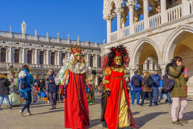 Venice, Italy - February 28, 2022: Group dressed in traditional costumes, in Riva degli Schiavoni waterfront, part of the Venice Mask Carnival, Veneto, Italy