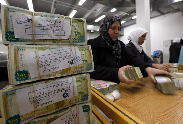 FILE - In this January 13, 2010 file photo, Syrian employees stack packets of Syrian currency in the Central Syrian Bank, in Damascus, Syria. On Tuesday, March 16, 2021, Syrian President Bashar Assad issued a decree granting hundreds of thousands of public sector workers and soldiers a one-time financial stimulus, equivalent to an average monthly salary of 50,000 Syrian pounds, which is nearly $11 on the black market. It comes as the national currency is crashing, now at 4,000 Syrian pounds to the dollar on the black market, compared to 700 a year ago. (AP Photo/Hussein Malla, File)