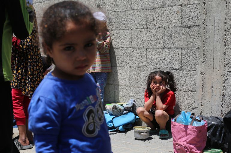 Palestinian children wait near a charity kitchen distributing portions of cooked food at the Nuseirat refugee camp in the central Gaza Strip on May 5, 2025.