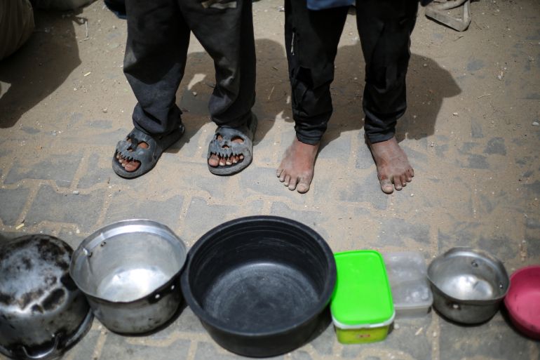 TOPSHOT - Palestinian children stand over empty containers at a food distribution centre in the Nuseirat camp for refugees, in the central Gaza Strip, on April 30, 2025.