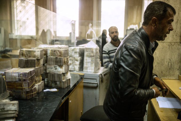 DAMASCUS, SYRIA - DECEMBER 24: An employee works in front of stacks of Syrian pounds at the exchange department at the Central Bank Of Syria on December 24, 2024 in Damascus, Syria. On December 8, rebel forces in Syria retook the capital and several other cities from longtime ruler Bashar al-Assad, who fled the country for Moscow. The fall of the Assad regime marks a new chapter for Syria, which has been mired in a multi-party civil war since 2011, sparked by the Arab Spring uprisings. (Photo by Chris McGrath/Getty Images)