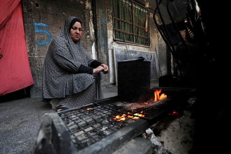 FILE PHOTO: A woman cooks as she shelters in an UNRWA-affiliated school in Jabalia refugee camp, in the northern Gaza Strip, May 8, 2025. REUTERS/Mahmoud Issa/File Photo
