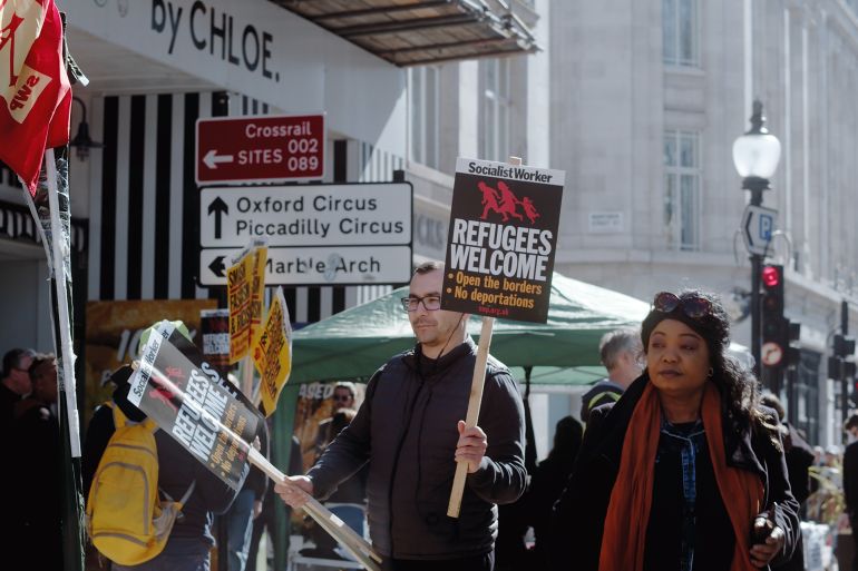 London, UK - 03 19 2022: A man protester at Portland Place holding a sign, Socialist Worker… Refugees Welcome…’, for the yearly ‘March Against Racism’, held around ‘UN Anti Racism Day’.; Shutterstock ID 2140670613; purchase_order: AJA; job: ; client: ; other: